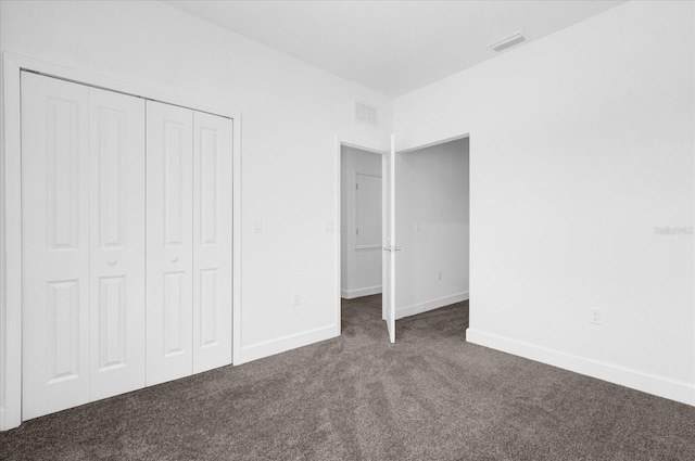 unfurnished bedroom with dark carpet and a closet