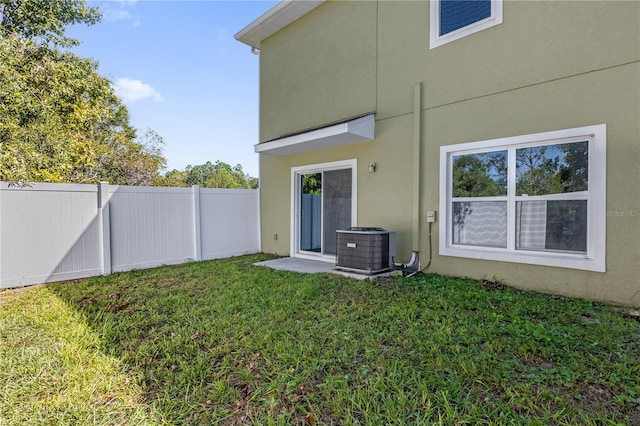 rear view of house with cooling unit and a lawn