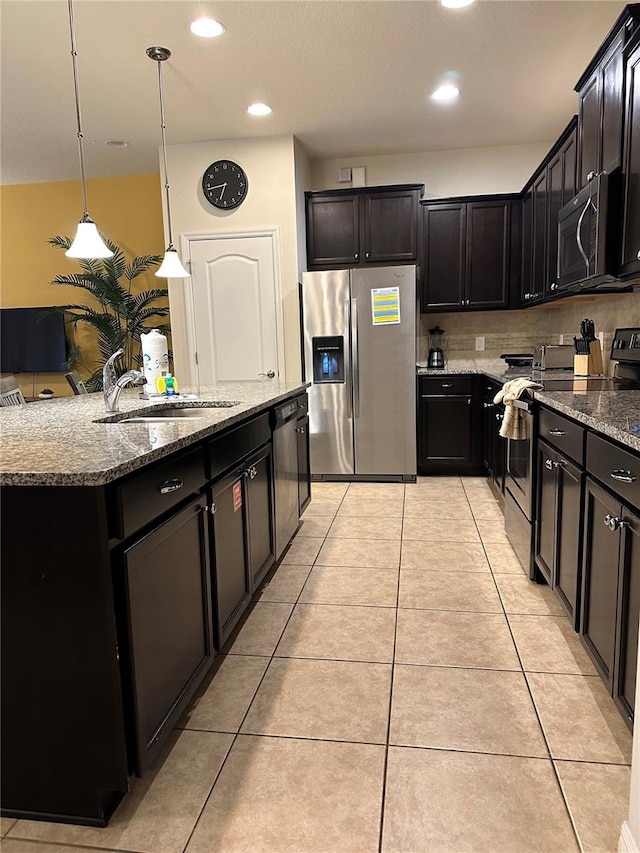 kitchen with hanging light fixtures, stainless steel appliances, a center island with sink, sink, and light tile patterned floors