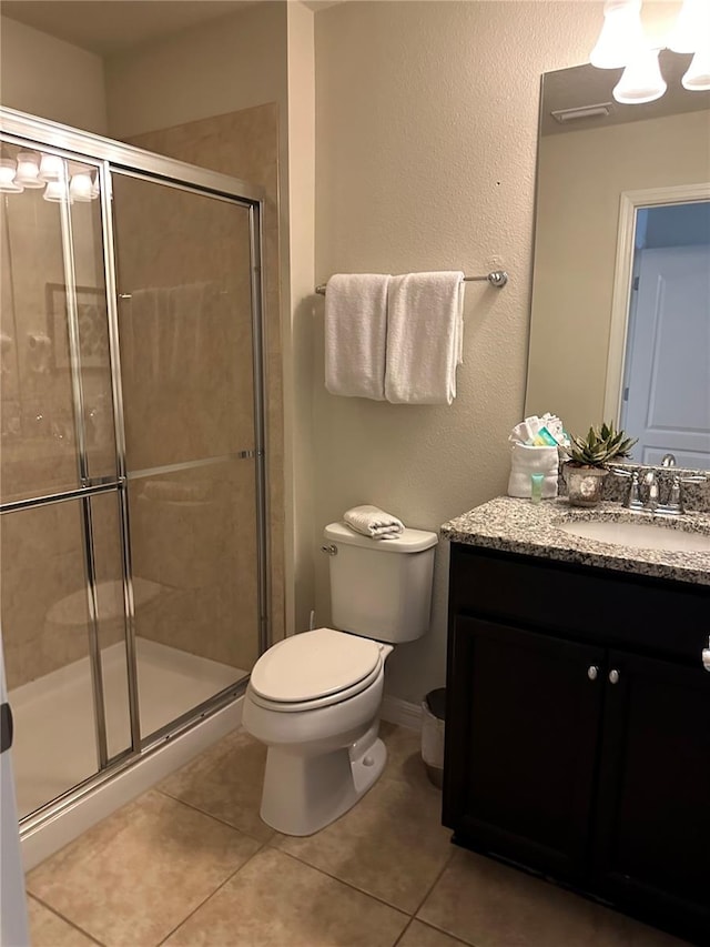 bathroom with vanity, a shower with shower door, toilet, and tile patterned flooring