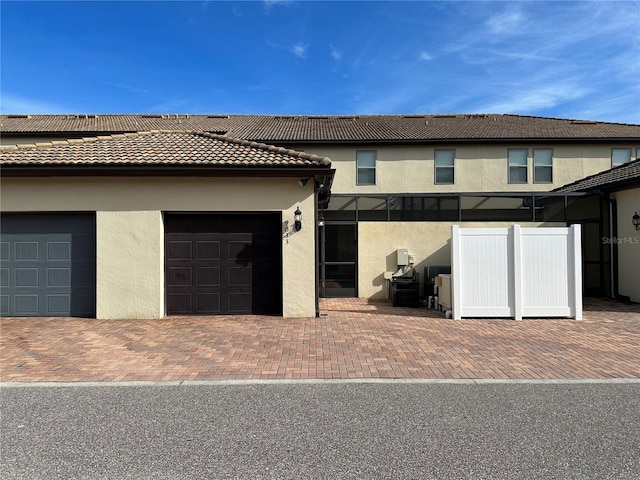 9033 Rhodes St, Kissimmee, FL 34747 - rear view of house with stucco siding, a tiled roof, an attached garage, and decorative driveway