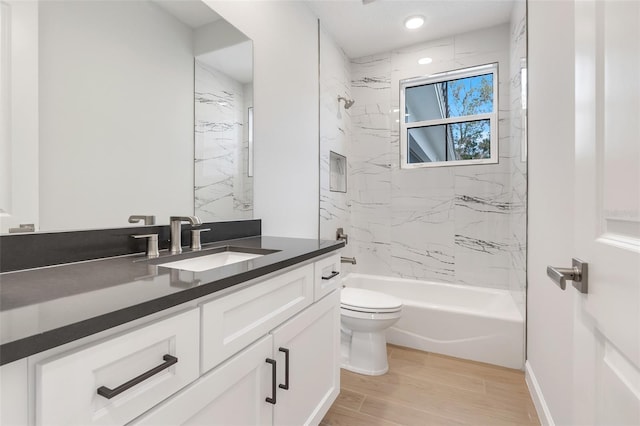 full bathroom featuring vanity, tiled shower / bath combo, hardwood / wood-style flooring, and toilet