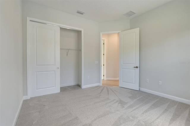 unfurnished bedroom with a closet and light colored carpet