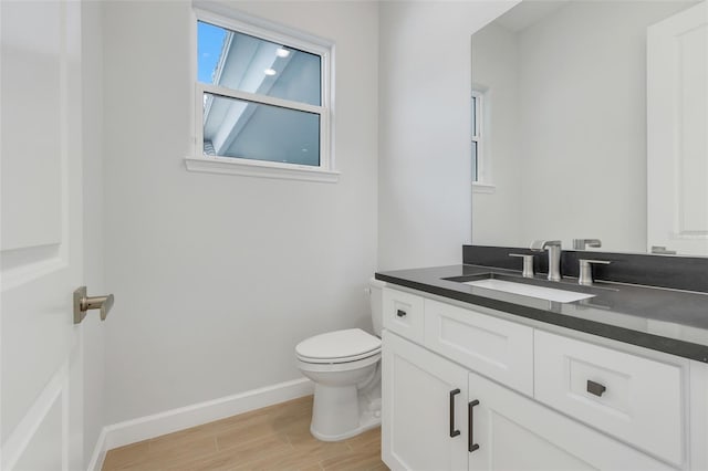 bathroom with toilet, hardwood / wood-style flooring, and vanity