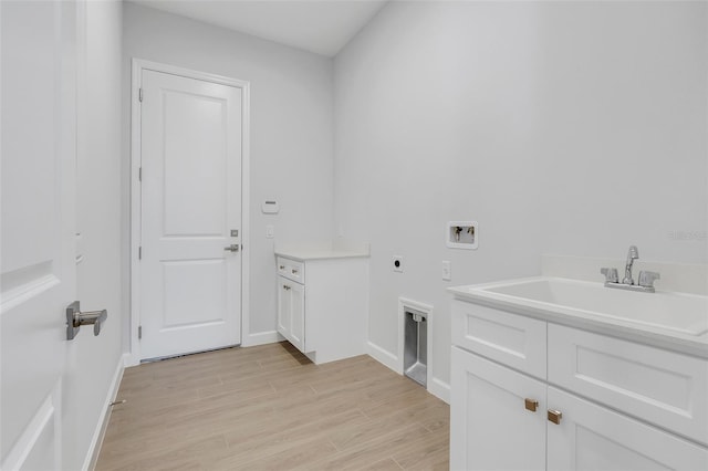 clothes washing area featuring hookup for a washing machine, light hardwood / wood-style flooring, sink, electric dryer hookup, and cabinets