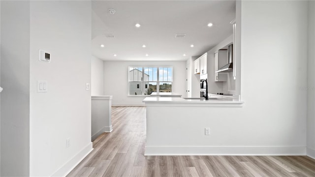 kitchen with light wood finished floors, recessed lighting, light countertops, white cabinets, and baseboards