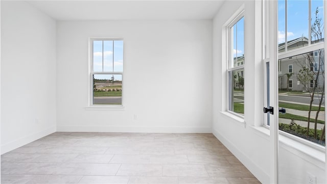 unfurnished room featuring a healthy amount of sunlight and baseboards