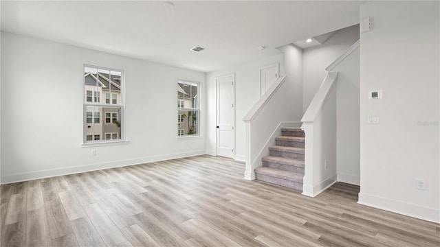 spare room with light wood-style flooring, visible vents, stairway, and baseboards