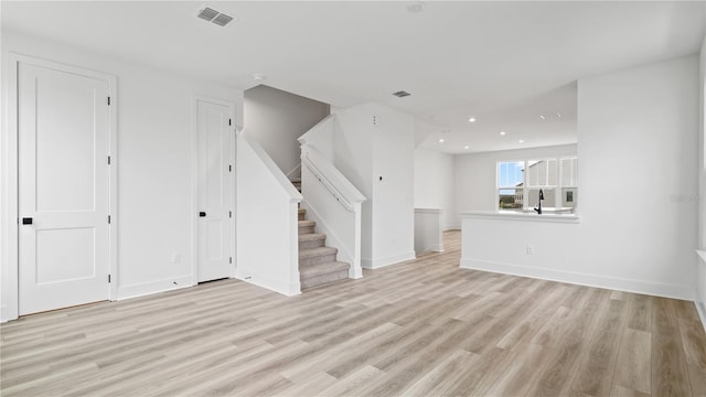 unfurnished living room featuring light wood finished floors, recessed lighting, visible vents, stairway, and baseboards