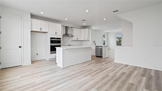 kitchen with double wall oven, visible vents, a center island, dishwasher, and wall chimney exhaust hood