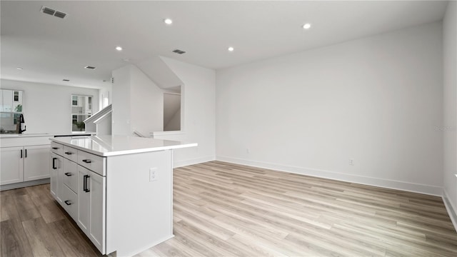 kitchen with recessed lighting, a kitchen island, visible vents, light countertops, and light wood-type flooring