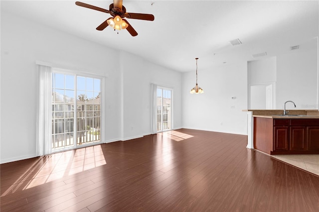 unfurnished living room featuring baseboards, visible vents, a ceiling fan, wood finished floors, and a sink