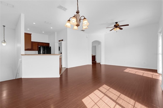 unfurnished living room featuring arched walkways, recessed lighting, ceiling fan with notable chandelier, dark wood-style flooring, and visible vents