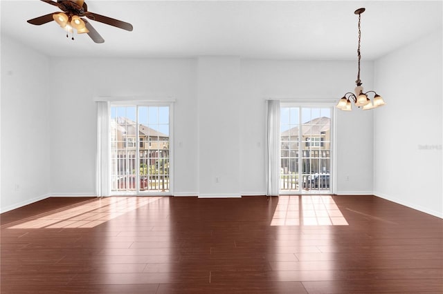 spare room with plenty of natural light, baseboards, dark wood-type flooring, and ceiling fan with notable chandelier