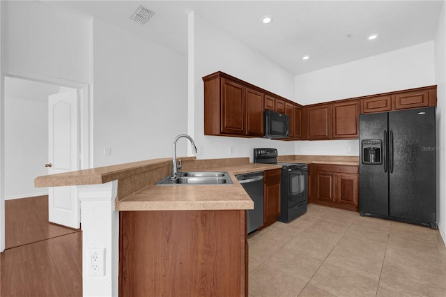 kitchen featuring light tile patterned floors, light countertops, a sink, a peninsula, and black appliances