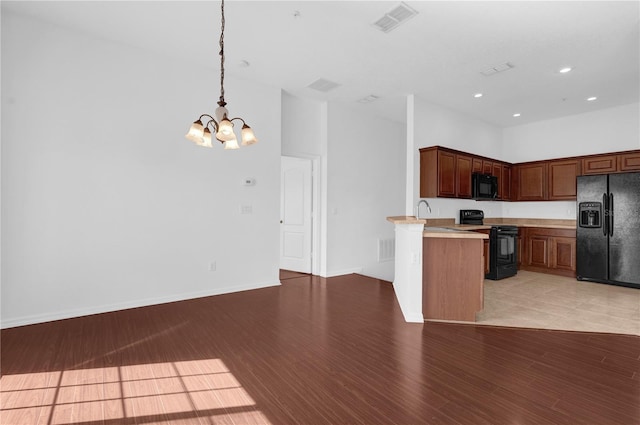 kitchen featuring light countertops, hanging light fixtures, visible vents, light wood-style floors, and black appliances