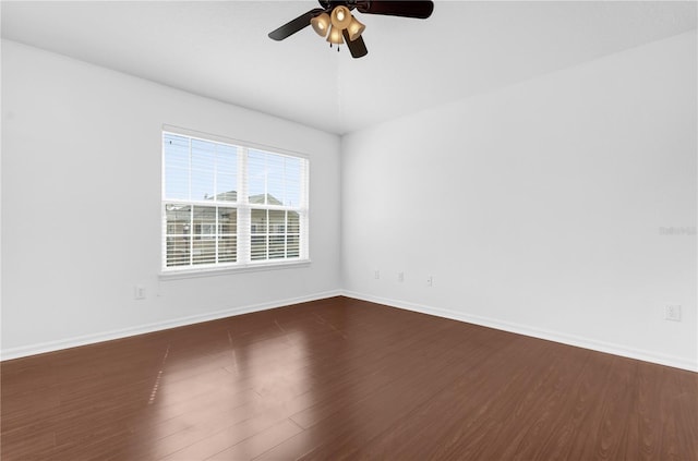 unfurnished room featuring dark wood-type flooring, ceiling fan, and baseboards