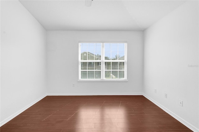 spare room with dark wood-type flooring and baseboards