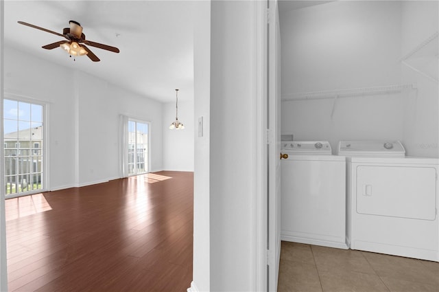 washroom with washing machine and dryer, wood finished floors, baseboards, and ceiling fan with notable chandelier