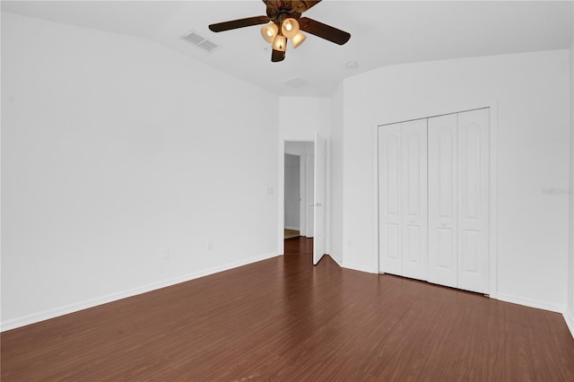 unfurnished bedroom with lofted ceiling, dark wood-type flooring, visible vents, and baseboards