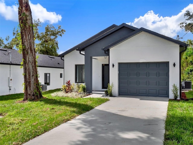 view of front of property with a front yard, a garage, and central AC unit