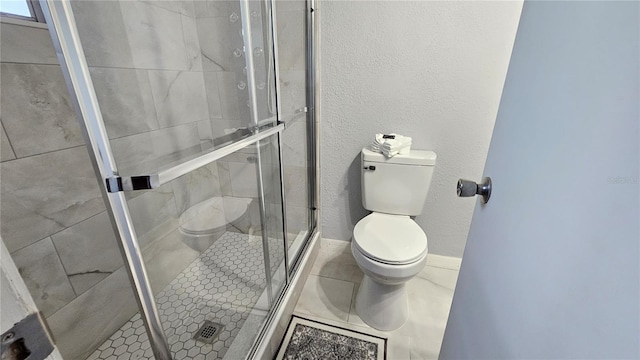 bathroom featuring tile patterned floors, toilet, and a shower with shower door