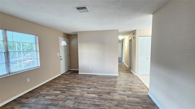 empty room featuring a textured ceiling and dark wood-type flooring