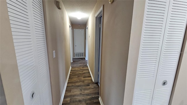 hall with a textured ceiling and dark hardwood / wood-style floors