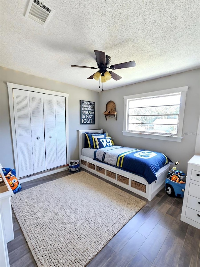 bedroom featuring a textured ceiling, a closet, ceiling fan, and dark wood-type flooring