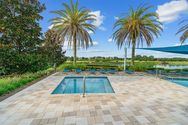 view of swimming pool featuring a patio area and a water view