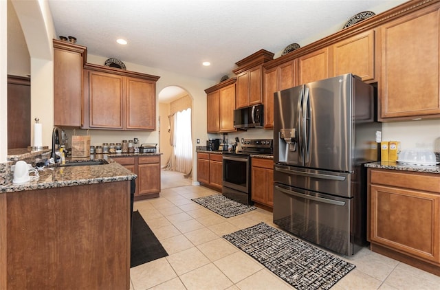 kitchen with light tile patterned flooring, appliances with stainless steel finishes, sink, and dark stone counters