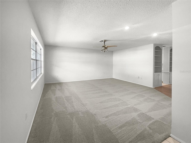 unfurnished room featuring a textured ceiling, carpet flooring, and ceiling fan