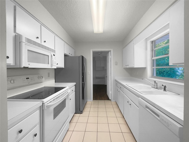 kitchen with a textured ceiling, white cabinetry, light tile patterned flooring, sink, and white appliances