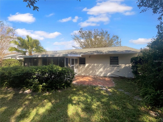 back of property with a yard and a sunroom