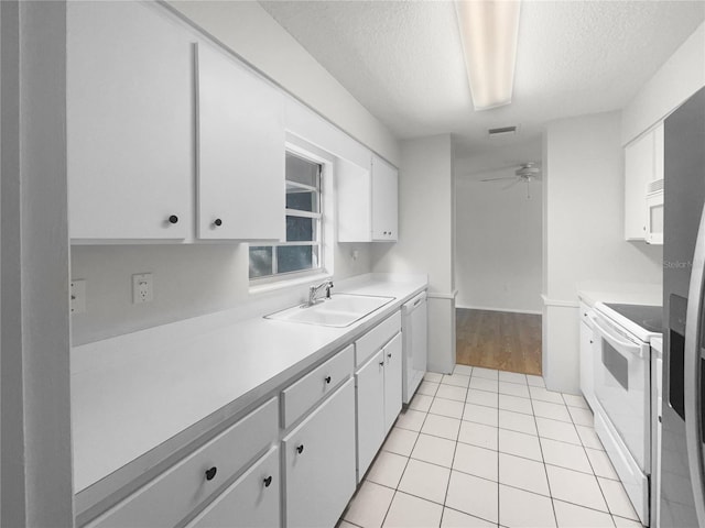 kitchen featuring sink, light tile patterned floors, white cabinetry, a textured ceiling, and white appliances