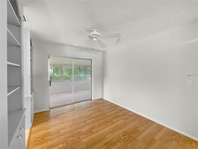 spare room featuring a textured ceiling, light wood-type flooring, and ceiling fan