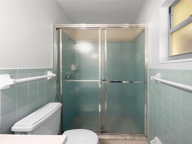 bathroom with tile walls, toilet, and an enclosed shower