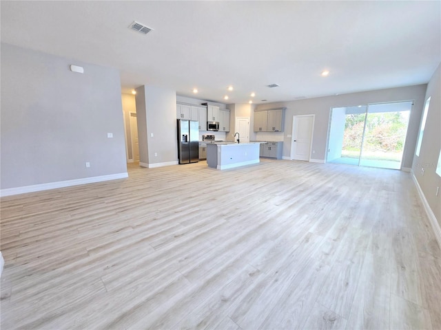 unfurnished living room featuring sink and light hardwood / wood-style flooring