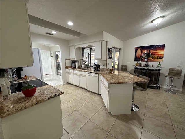 kitchen with lofted ceiling, kitchen peninsula, a breakfast bar, white cabinetry, and white appliances