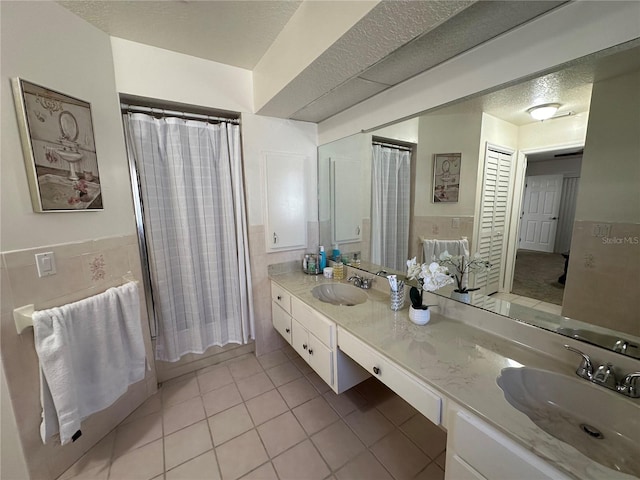 bathroom featuring vanity, a textured ceiling, walk in shower, and tile patterned flooring