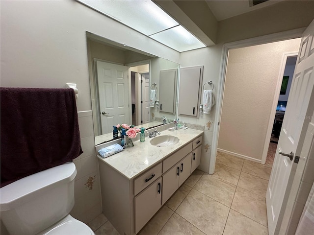 bathroom with tile walls, vanity, toilet, and tile patterned flooring