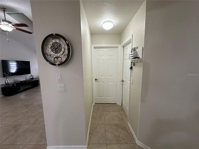 corridor featuring a textured ceiling and light tile patterned flooring