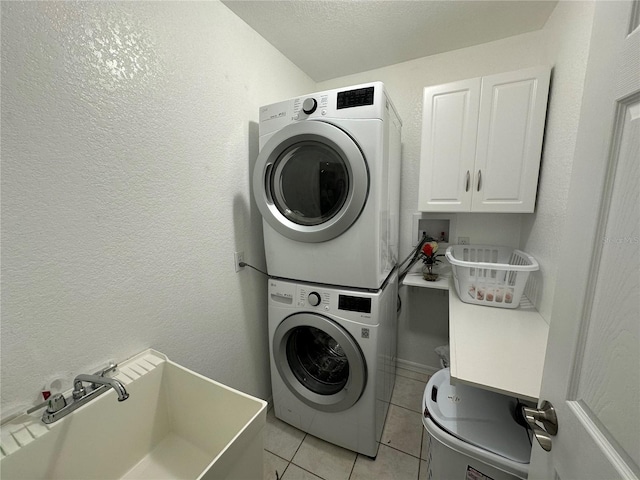 washroom featuring light tile patterned floors, a textured ceiling, sink, and stacked washer and clothes dryer