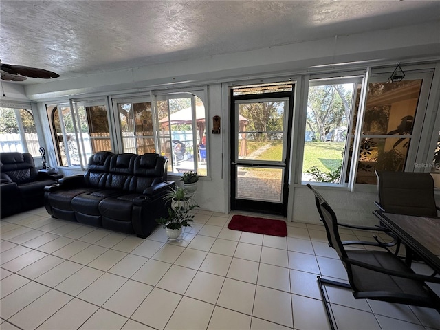 living room with ceiling fan, a textured ceiling, and light tile patterned flooring