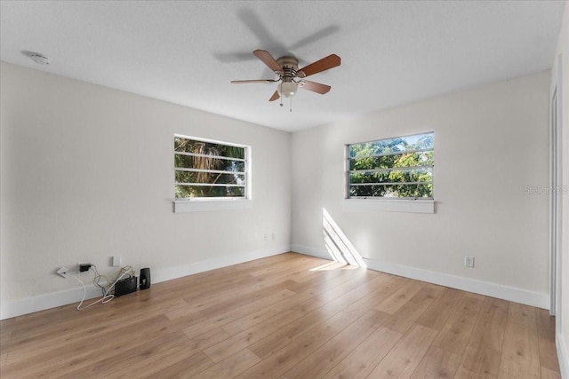 spare room with light hardwood / wood-style floors, a wealth of natural light, and ceiling fan