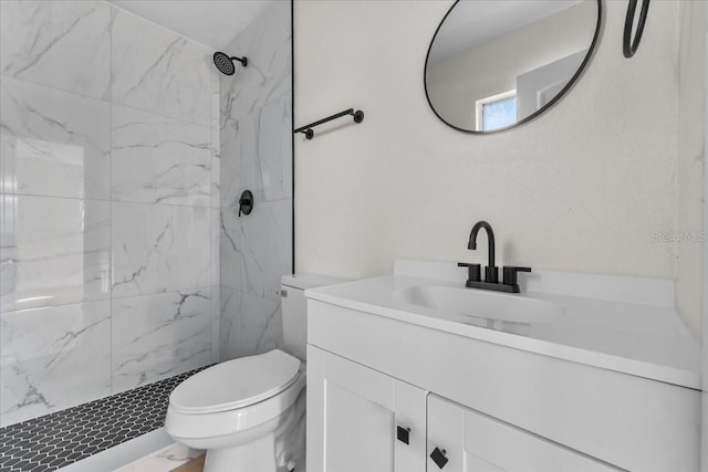 bathroom with toilet, vanity, and a tile shower