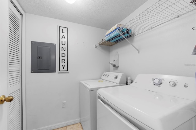 laundry room with light tile patterned flooring, a textured ceiling, electric panel, and washing machine and clothes dryer