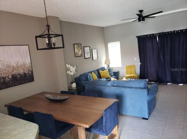 living room featuring ceiling fan with notable chandelier and a textured ceiling