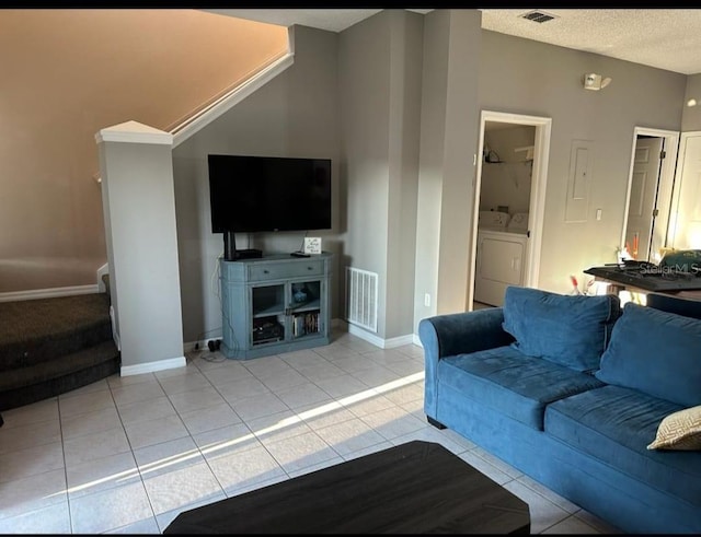 tiled living room with a textured ceiling and independent washer and dryer