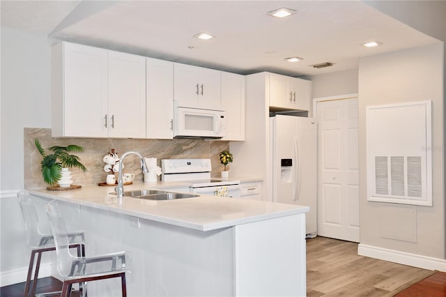 kitchen with backsplash, white appliances, sink, light hardwood / wood-style flooring, and white cabinetry